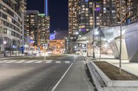 an empty street in an urban area lit up at night, along with a building and clock tower