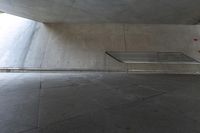 a concrete bench on the outside wall of a building with a skylight over it