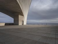 a large, concrete structure on the edge of a lake under an overcast sky