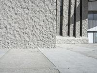 the sidewalk outside of the building is stone and cement with a green fire hydrant and two people