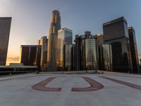 there is a city view of the city with buildings on the horizon at sunset with red letters on the concrete