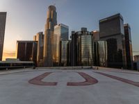 there is a city view of the city with buildings on the horizon at sunset with red letters on the concrete