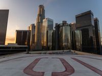 there is a city view of the city with buildings on the horizon at sunset with red letters on the concrete