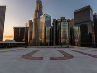 there is a city view of the city with buildings on the horizon at sunset with red letters on the concrete