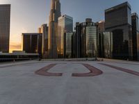 there is a city view of the city with buildings on the horizon at sunset with red letters on the concrete