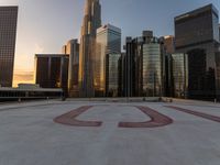 there is a city view of the city with buildings on the horizon at sunset with red letters on the concrete