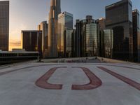 there is a city view of the city with buildings on the horizon at sunset with red letters on the concrete