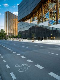 empty city street in front of a building with reflective windows and bicyclist in foreground