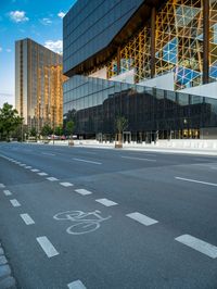 empty city street in front of a building with reflective windows and bicyclist in foreground