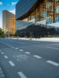 empty city street in front of a building with reflective windows and bicyclist in foreground