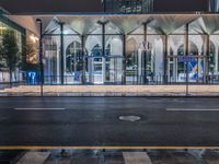 a large glass building with a glass entrance and street lights at night time in front