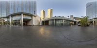 a large glass building with a curved entry way in front of it and cars around