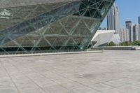 a large glass building near a city with skyscrapers in the background with a woman holding an umbrella