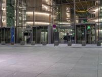 a very big square with some stairs and windows at night time with a fire hydrant sitting in front of it