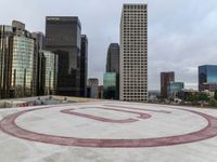 an outdoor round concrete surface in front of tall buildings and the letter u with an over - sized number