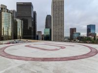 an outdoor round concrete surface in front of tall buildings and the letter u with an over - sized number