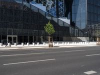 the empty road runs near the black and silver building with windows and a clock hanging on it