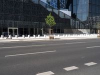 the empty road runs near the black and silver building with windows and a clock hanging on it