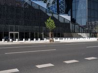 the empty road runs near the black and silver building with windows and a clock hanging on it