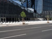 the empty road runs near the black and silver building with windows and a clock hanging on it