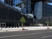 the empty road runs near the black and silver building with windows and a clock hanging on it