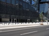 the empty road runs near the black and silver building with windows and a clock hanging on it