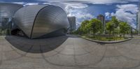 a giant building with an unusual circular object in front of it in a city park