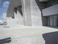 this is an outdoor courtyard with stone steps and a curved concrete wall, that stretches to the outside