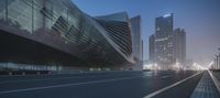 a wide shot of a night scene with cars driving by in front of a futuristic office building