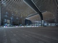 large modern city building with lights reflecting in the windows and concrete flooring and tiles