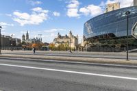 the big building is by the city street in the daytime and people walk on the sidewalk