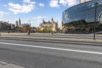 the big building is by the city street in the daytime and people walk on the sidewalk