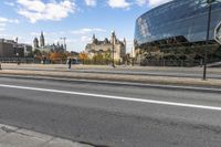 the big building is by the city street in the daytime and people walk on the sidewalk