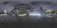 a fisheye lens picture of a public transit station at night in the usa with street lights lit up around it