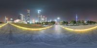 this is a skateboard park full of lights and curves, at night time with lots of buildings in the background