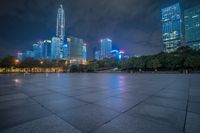 a city skyline lit up with many buildings in the background and a park with benches at its base