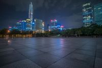 a city skyline lit up with many buildings in the background and a park with benches at its base