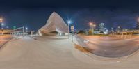 a futuristic looking structure sitting on the side of a street in a city at night