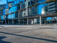 a city street and sidewalk with tall buildings reflecting in the glass windows of it's sides