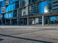 a city street and sidewalk with tall buildings reflecting in the glass windows of it's sides