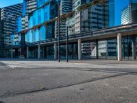 a city street and sidewalk with tall buildings reflecting in the glass windows of it's sides