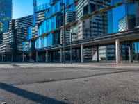 a city street and sidewalk with tall buildings reflecting in the glass windows of it's sides