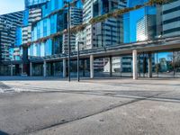 a city street and sidewalk with tall buildings reflecting in the glass windows of it's sides