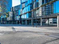 a city street and sidewalk with tall buildings reflecting in the glass windows of it's sides