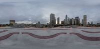 a skateboarder jumps at a concrete park with the city skyline in the background