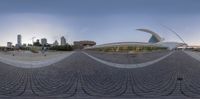 an open walkway and buildings with the skyline in the background behind them seen from the reflection of a fish eye lens