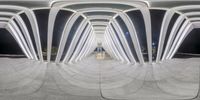 the walkway is made of curved metal frames with several lighting spots visible below them on concrete ground