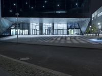 a very large open building with lights on at night time with a fountain in the middle