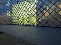 a building with multiple square patterns on the outside side, with light reflecting in the windows