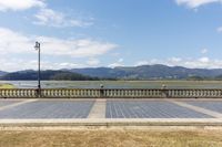 a park bench sits on the edge of a stone walkway looking out at a lake and mountains